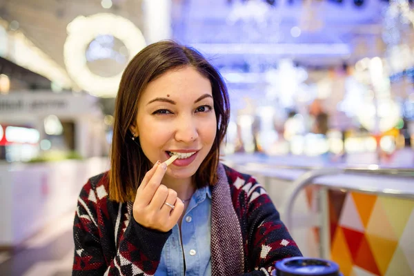Красива біла молода жінка обідає фаст-фудом смажену картоплю в кафе в торговому центрі . — стокове фото