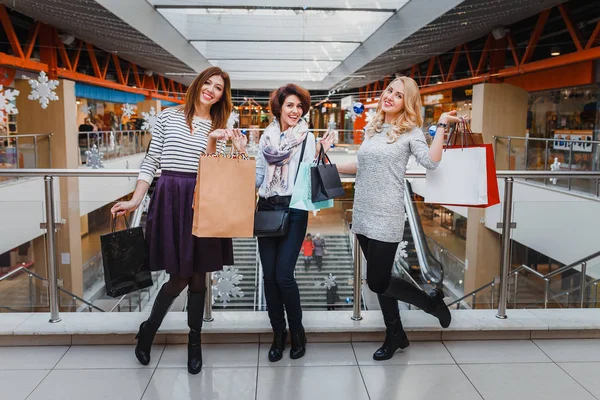Tři krásné mladé ženy s nákupní tašky při pohledu na fotoaparát v obchoďáku — Stock fotografie