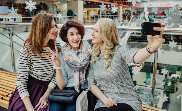 三个妇女女朋友在新的一年在商场购物，并考虑在智能手机的拍照休息 — 图库照片