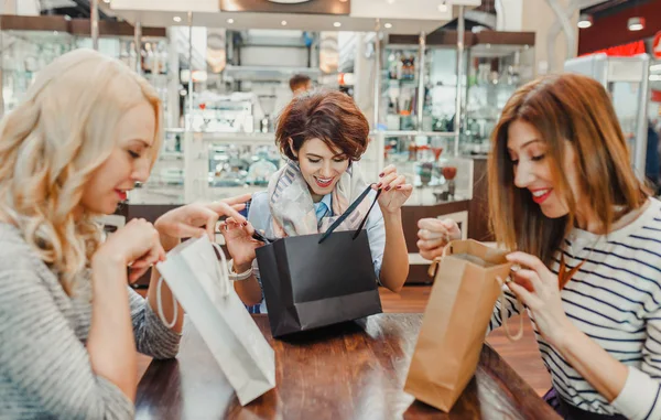 Mujeres jóvenes felices mirando en bolsas de compras en el café del centro comercial. Venta y concepto actual — Foto de Stock