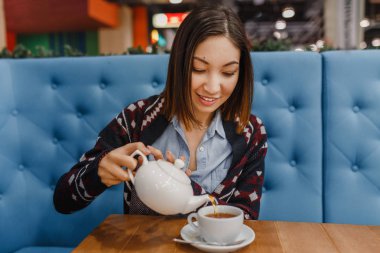 bir fincan çay dökme ve kafede gülümseyen surat kadın