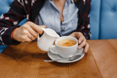 Su ısıtıcısı çay bir fincan süt dökülen kadın