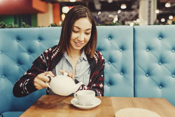 Смайлик наливает чашку чая и улыбается в кафе — стоковое фото