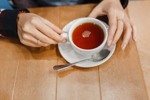 Retro yün kazak ahşap masa üzerine sıcak bir fincan çay kadınla eller — Stok fotoğraf