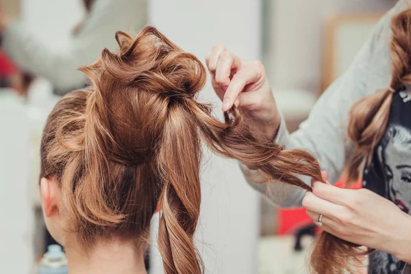 Alto proceso de creación de peinado en el salón de peluquería con moño elegante. Cabellos rubios y rojos — Foto de Stock