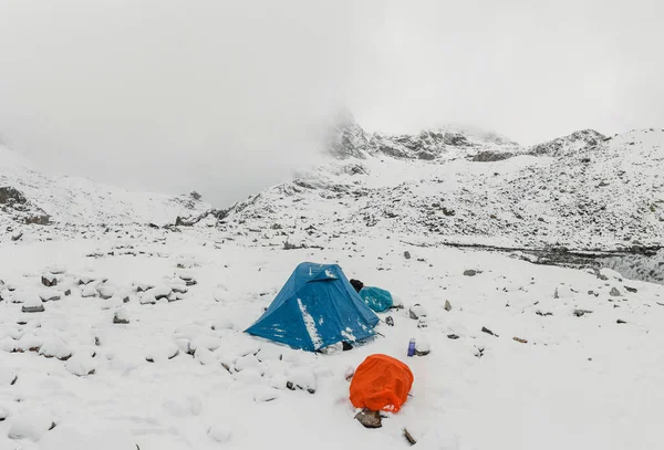 A bright snow survival shelter tent in a snow blizzard in the mountains