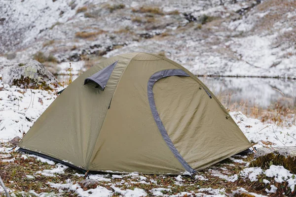 A bright snow survival shelter tent in a snow blizzard in the mountains