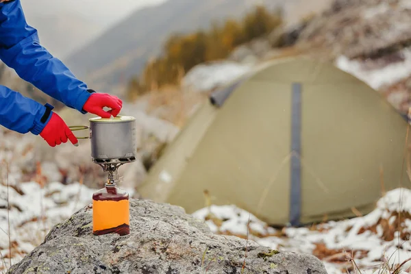 Stufa a getto da campeggio a cartuccia a gas con moderna pentola in titanio su uno sfondo della tenda durante le escursioni — Foto Stock