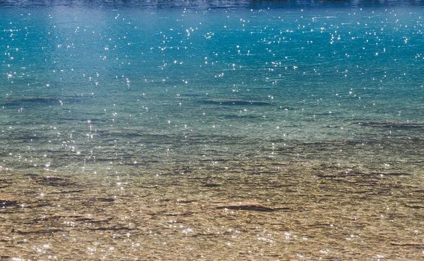 Bel primo piano di una superficie di acqua frizzante in un lago di montagna blu — Foto Stock