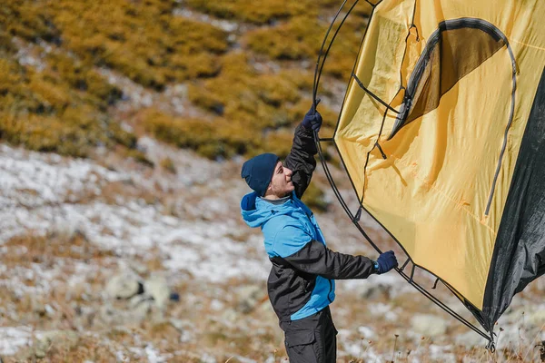 Junger Mann hebt Zelt auf Zeltreise in den Bergen mit Kopierraum — Stockfoto