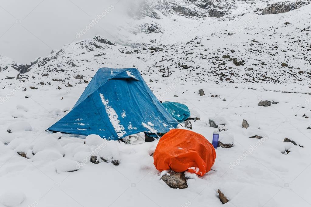 A bright snow survival shelter tent in a snow blizzard in the mountains