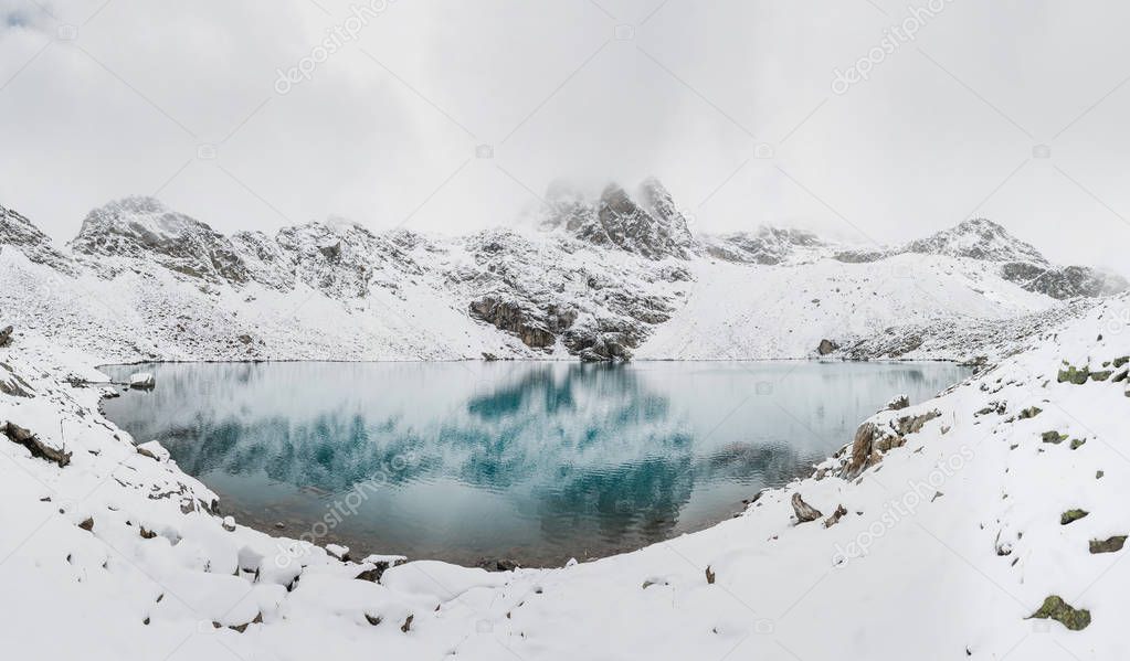 panorama of incredible blue lake surrounded by a chain of high snow-capped mountains