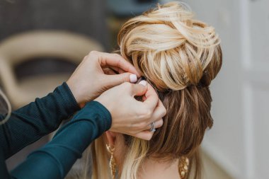 Kuaför karmaşık ve güzel saç modeli üst topuz yapar. Akşam ve düğün tarzı için uygun