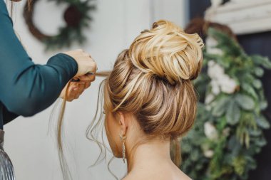 Kuaför karmaşık ve güzel saç modeli üst topuz yapar. Akşam ve düğün tarzı için uygun
