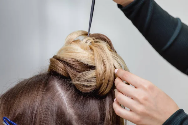 Coiffeur fait un chignon supérieur complexe et belle coiffure. Convient pour le soir et le style de mariage — Photo