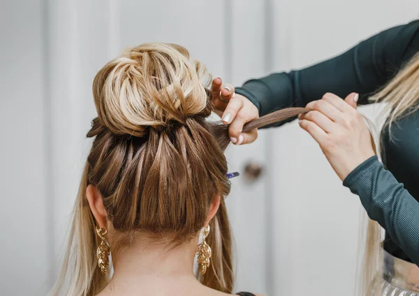 Hairdresser makes complex and beautiful hairstyle upper bun. Suitable for evening and wedding style — Stock Photo, Image