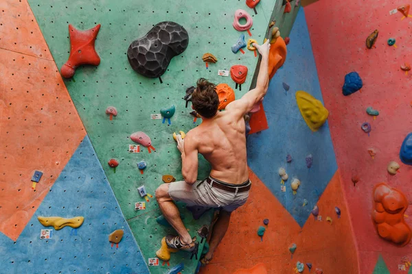 Muscular e apto topless homem exercício bouldering e escalada interior na parede artificial — Fotografia de Stock