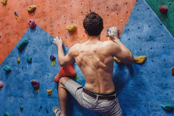 Muscular e apto topless homem exercício bouldering e escalada interior na parede artificial — Fotografia de Stock