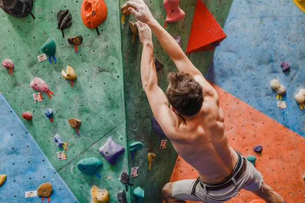 Muscular e apto topless homem exercício bouldering e escalada interior na parede artificial — Fotografia de Stock