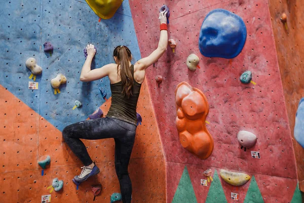 Joven mujer de fitness haciendo bouldering profesional en el gimnasio de escalada en interiores — Foto de Stock