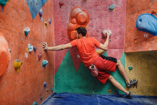 Joven caucásico hombre escalada en roca en el interior — Foto de Stock