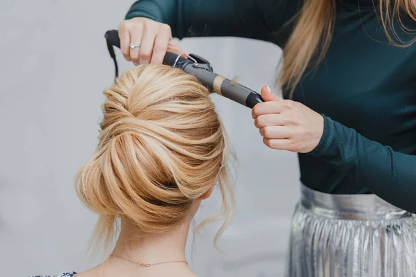 Primer plano de la mano del estilista usando rizador de trabajo para el cabello de la mujer cliente —  Fotos de Stock
