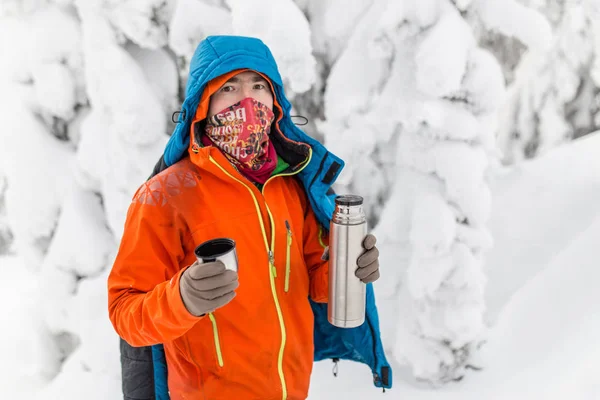 El hombre derrama té caliente del termo en el bosque de invierno —  Fotos de Stock