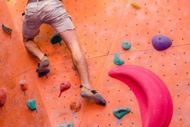 Uygun adam rock kapalı bouldering spor salonunda tırmanma, bacaklar yakın çekim
