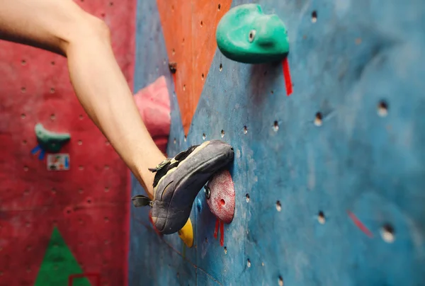 Voet in de schoenen van een man klimmen op kunstmatige boulder haak in sportschool — Stockfoto