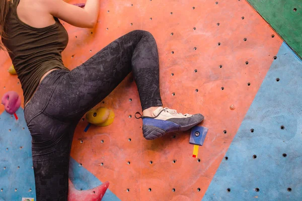 Foten av kvinnliga klättrare på konstgjord boulder. Närbild av professionella sko — Stockfoto