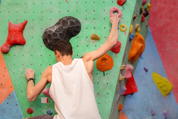 Fuerza y escalada deportiva masculina en un muro de escalada interior . — Foto de Stock