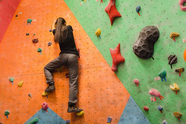 attractive young professional sport climber woman having training in the gym at artificial wall