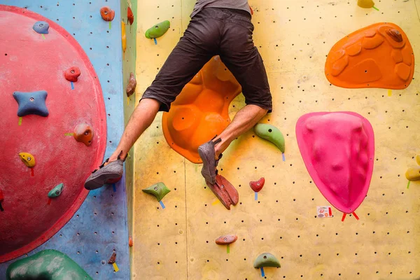 Entrenamiento de escalador masculino en la pared del gimnasio de bouldering, primer plano de los músculos de las piernas con zapatos — Foto de Stock