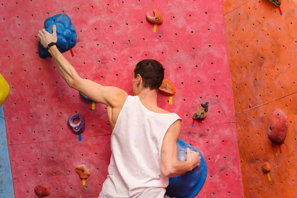 Força e esportivo masculino escalada em uma parede de escalada interior . — Fotografia de Stock