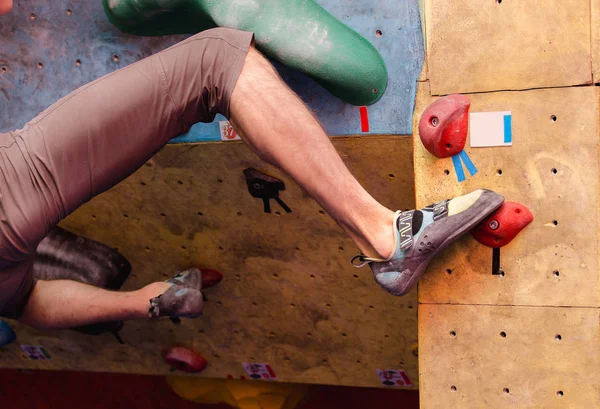 Foot in climbing shoes of a man on artificial boulder hook in gym — Stock Photo, Image