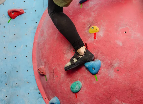 Voet met schoenen van vrouwelijke klimmer op kunstmatige Boulderwand bij sportschool — Stockfoto