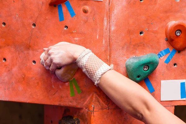 Ung kvinna klättra upp på väggen i gym, fokus å med bandage — Stockfoto