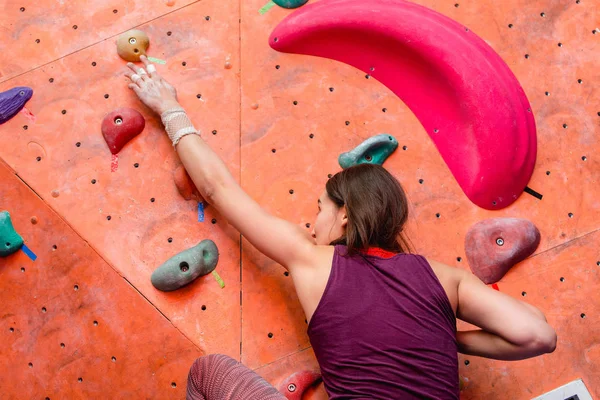 Young woman practicing in bouldering on a rock wall indoors — Stock Photo, Image