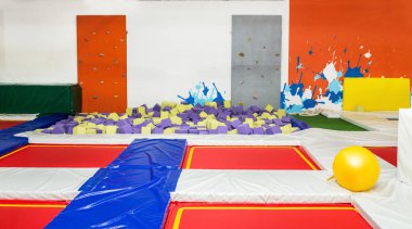 Bir çocuk spor tırmanma duvarı ve köpük çukur trambolin ile karmaşık renkli iç