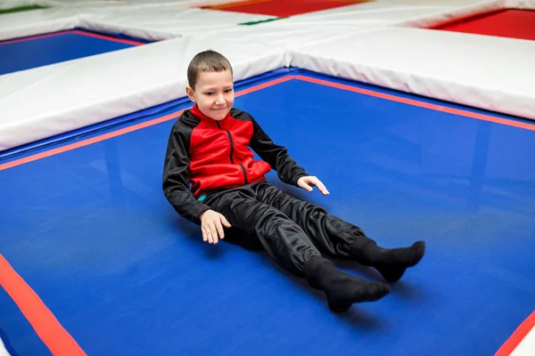 Lyckligt barn pojke i färgglad kostym avkopplande på studsmatta i idrott komplex — Stockfoto