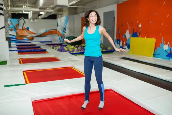 Hoppning ung kvinna i trampolin sportcenter inomhus — Stockfoto