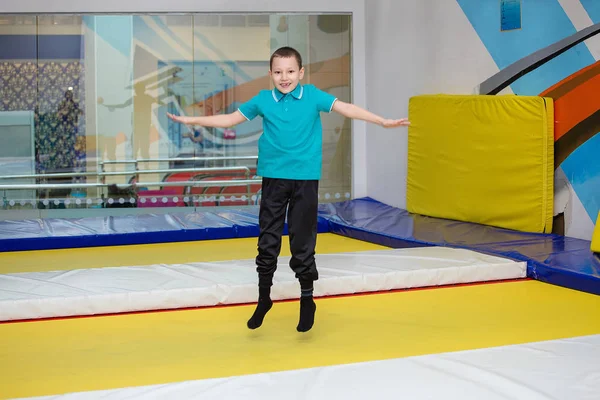 Мальчик прыгает высоко в полосатых колготках на большом батуте в детском спорткомплексе — стоковое фото