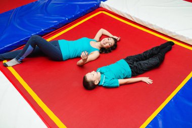 Güzel genç anne ve küçük oğlu parkında oynayan ve bir trambolin üzerinde yalan