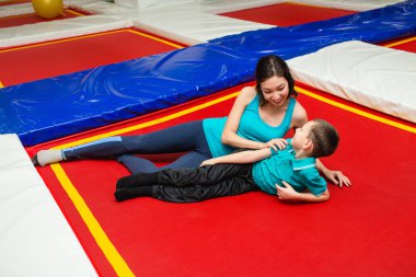 Güzel genç kadın ve büyüleyici küçük çocuk fitness trambolin salonunda yoga mat yatarken gülüyorsun