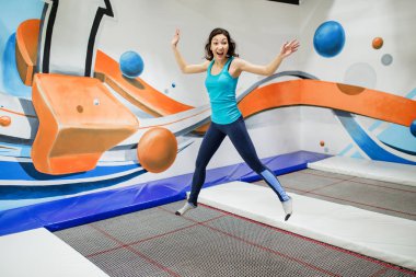 Fitness Park'ta bir trambolin üzerinde atlama ve exersice kapalı yapıyor genç kadın sporcu