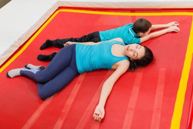 Anne ve oğlu yalan ve üzerinde trambolin birlikte kapalı dinlenme fitness salonunda.