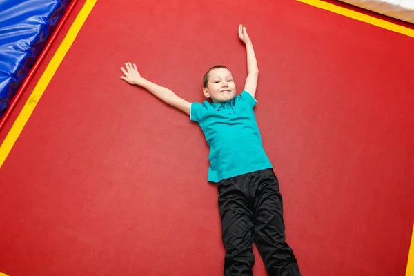 Мальчик прыгает и лежит, отдыхая на батуте, высокий угол зрения — стоковое фото
