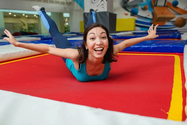 Молодая женщина прыгает на батуте и отдыхает в спортивном зале — стоковое фото
