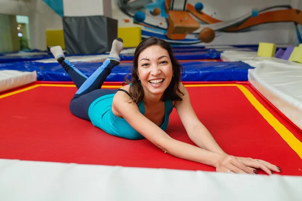 Mujer joven salta en el trampolín y descansa en el gimnasio deportivo — Foto de Stock