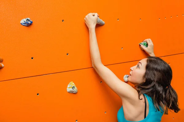 Αρχάριος θηλυκό ορειβάτης στο boulder αναρρίχηση τοίχου σε εσωτερικούς χώρους φτάνει στην κορυφή — Φωτογραφία Αρχείου